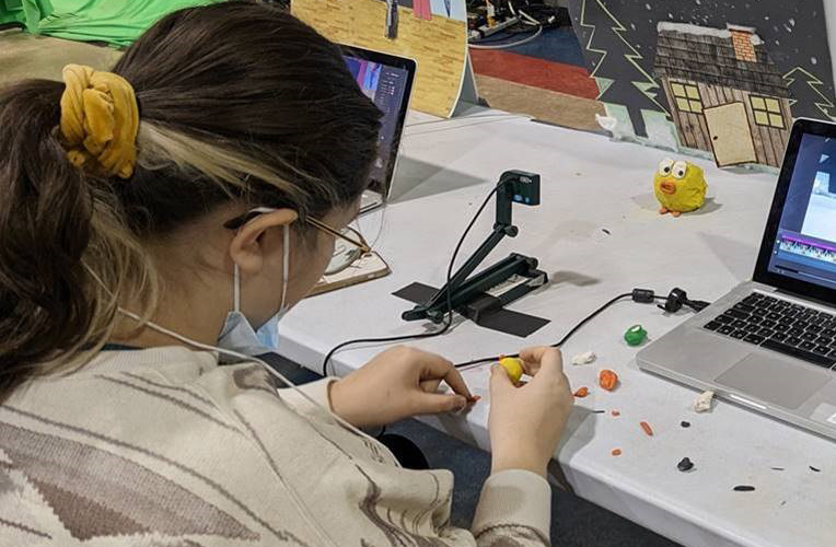 A student is creating something with clay pieces for a stop motion animation