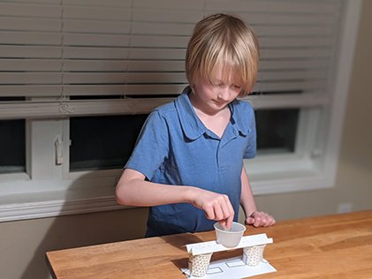 A student builds a bridge out of paper and paper cups