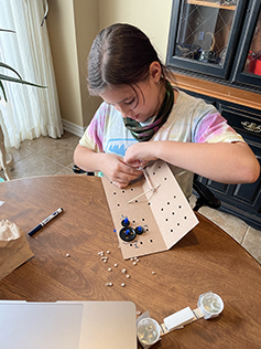 a student creates a machine with plastic gears and cardboard