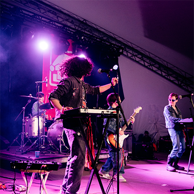 A rock band consisting of a pianist, bassist, guitarist and drummer performing on stage